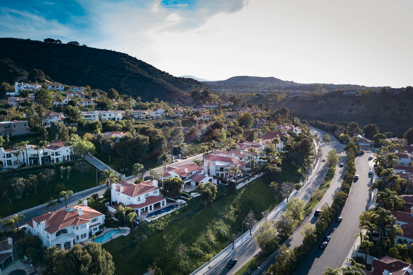 Aerial view of a gated Calabasas neighborhood with tile-roof homes along a hillside road